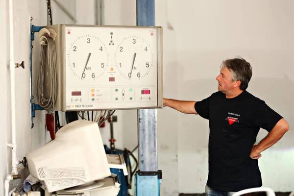 Ein Mechaniker prüft eine Prüfstandsanzeige für Fahrzeugtechnik in einer Werkstatt.