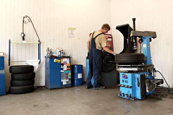 Mechaniker wechselt Reifen in einer Werkstatt mit moderner Reifenwechselmaschine.