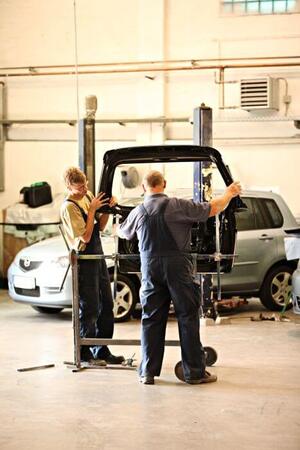 Zwei Automechaniker arbeiten in einer Werkstatt an einer Fahrzeugtür für die Autoreparatur.