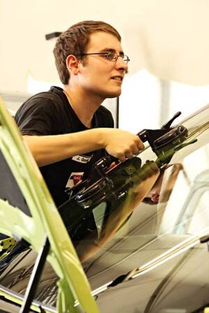 Ein Monteur installiert fachgerecht eine neue Frontscheibe bei der Autoglasreparatur.